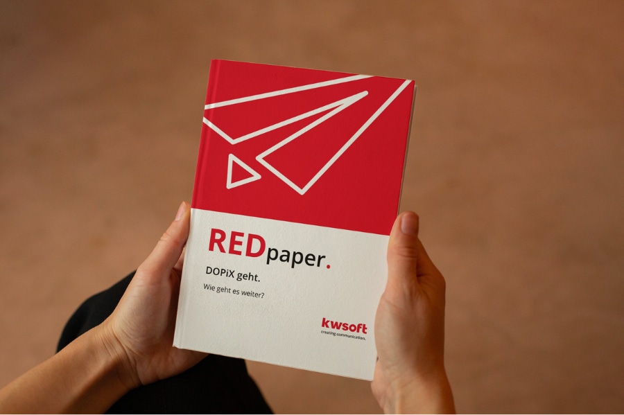 Obrázek zobrazuje osobu držící dokument REDpaper o náhradě „DOPiX“.